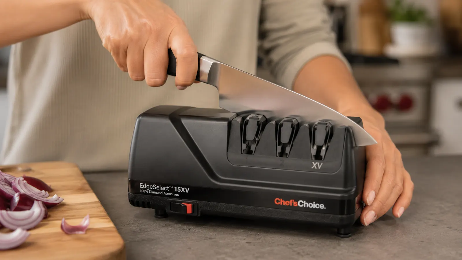 A hand pulling a chef's knife through the diamond abrasive slot of the Chef'sChoice 15XV sharpener at a steady angle