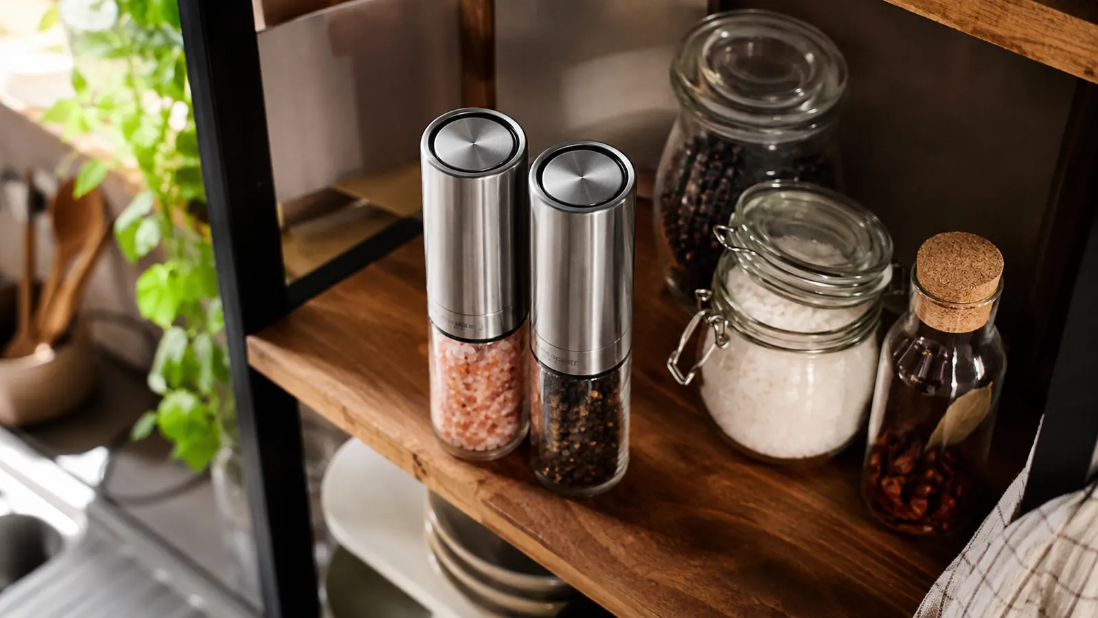 Both Circle Joy grinders sitting on an open shelf next to jars of peppercorns and coarse salt, ready for the next dinner