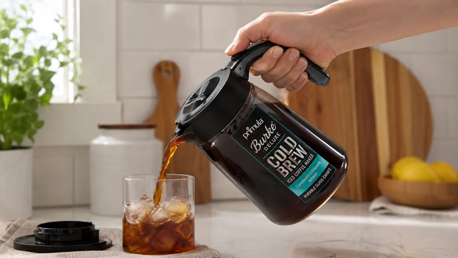 Hand pouring iced coffee one-handed from the Primula Burke Deluxe carafe using its comfort grip handle